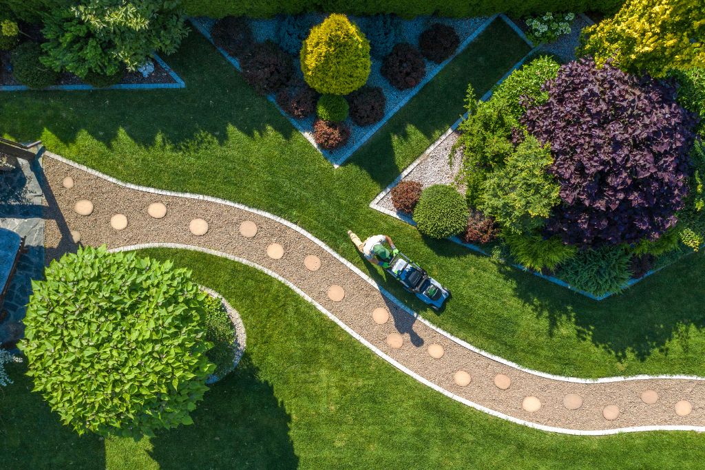 Aerial view showcasing a lush green lawn surrounding a charming house, highlighting the beauty of the landscape.